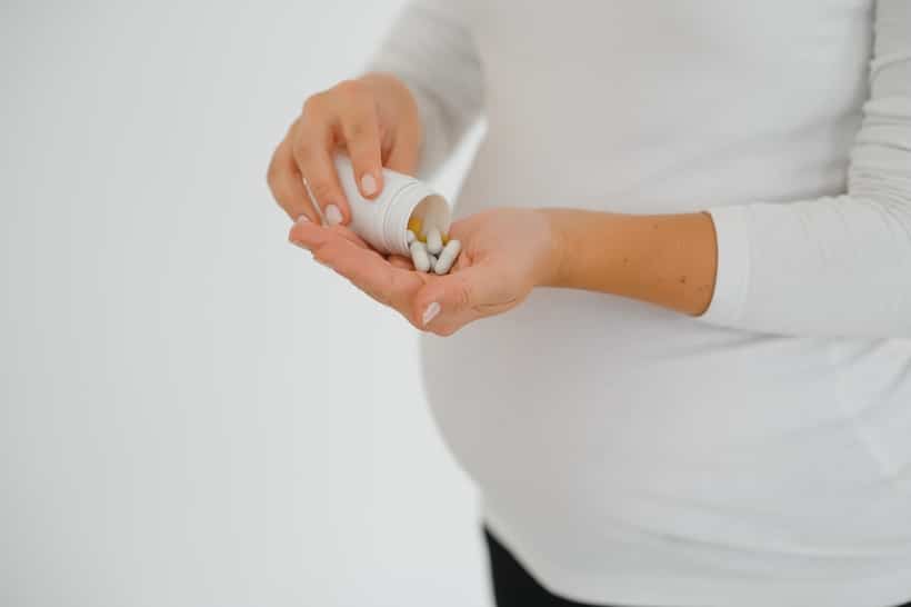 Deze afbeelding laat een vrouw zien die multivitamines slikt tijdens de zwangerschap.